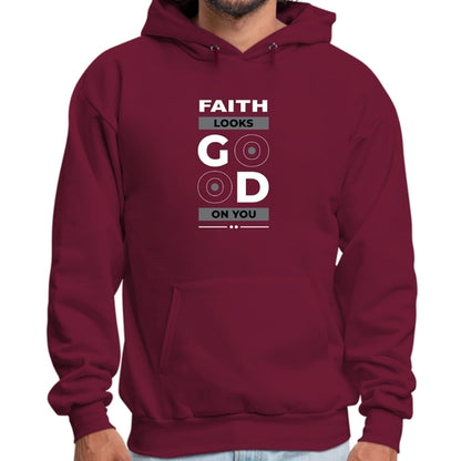 A person wearing a maroon Faith Looks Good Graphic Hoodie with the text "FAITH LOOKS GOOD ON YOU" printed on the front. The graphic hoodie features a stylish design with "GOOD" in larger, bold font. It has a front pocket and the person stands with their hands visible at their sides.