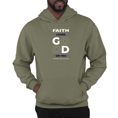 A person wearing an olive green Faith Looks Good Graphic Hoodie with a front pocket. The graphic hoodie features the text "FAITH LOOKS GOOD ON YOU" on the front, with artistic circles around the letters "O" in "GOOD". The person has their hands in the hoodie pocket.